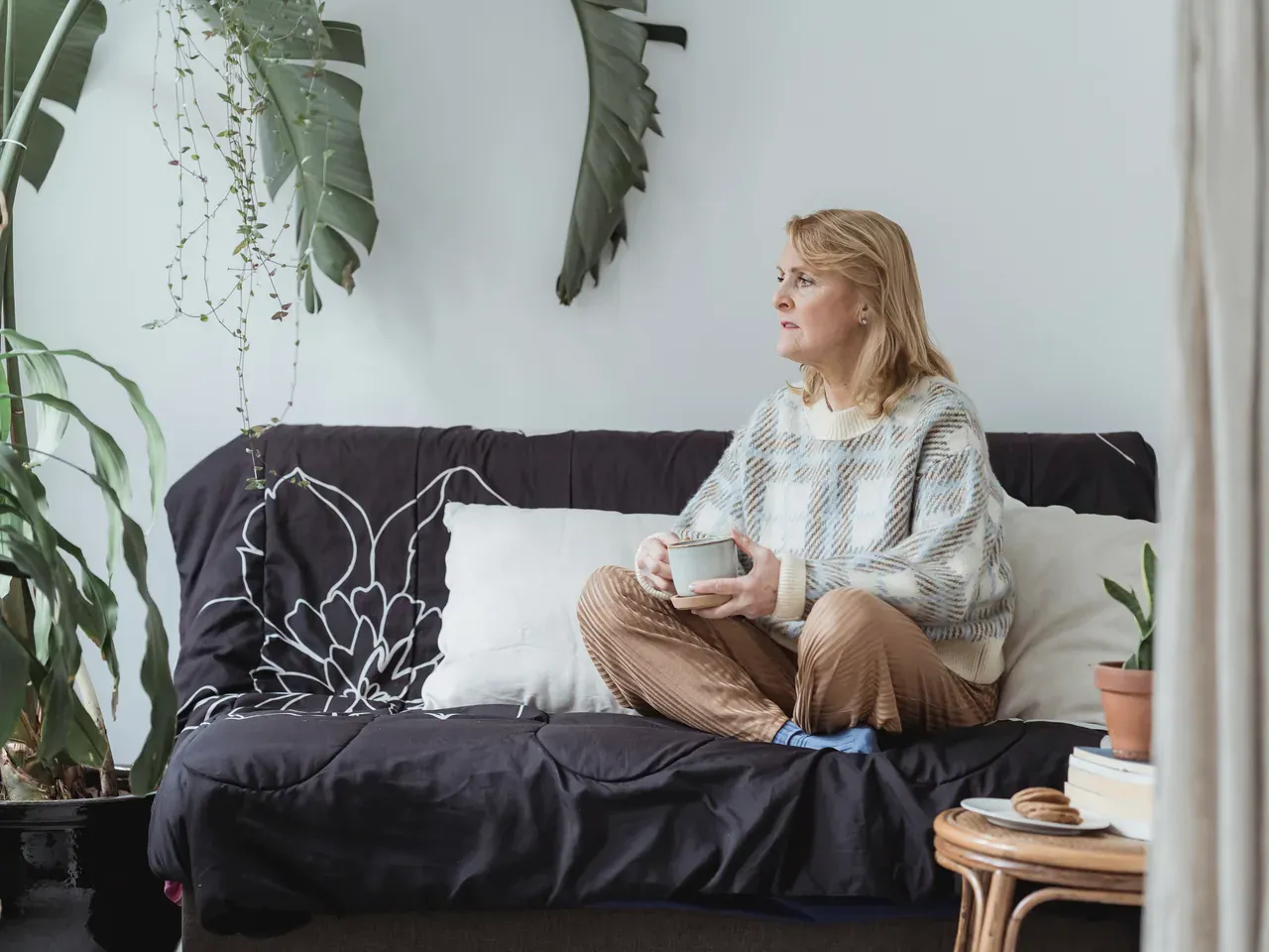 A woman sitting with a warm drink and taking a quiet pause before answering